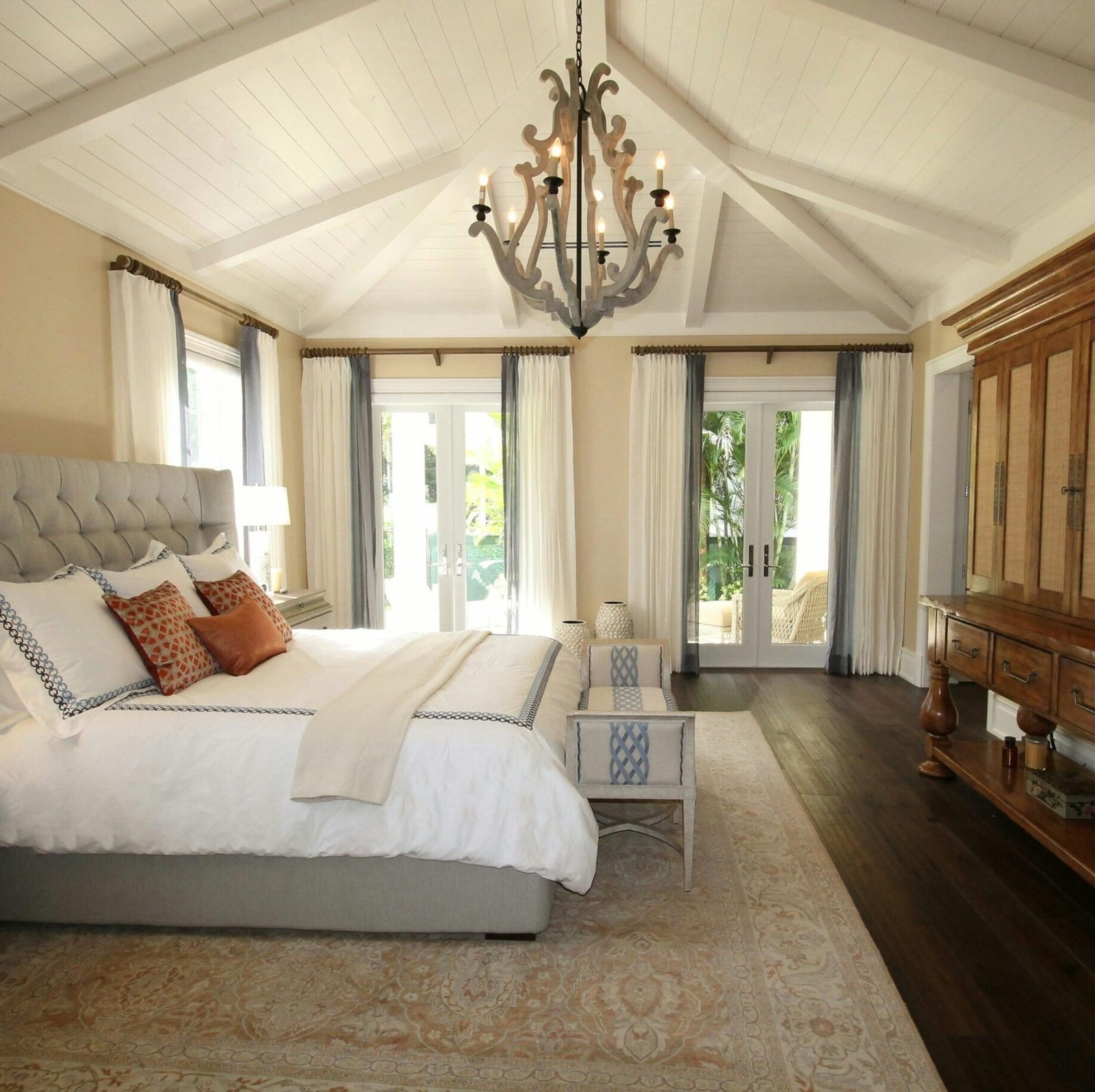 Stylish bedroom interior featuring a rustic chandelier, cozy bedding, and elegant wooden furniture.